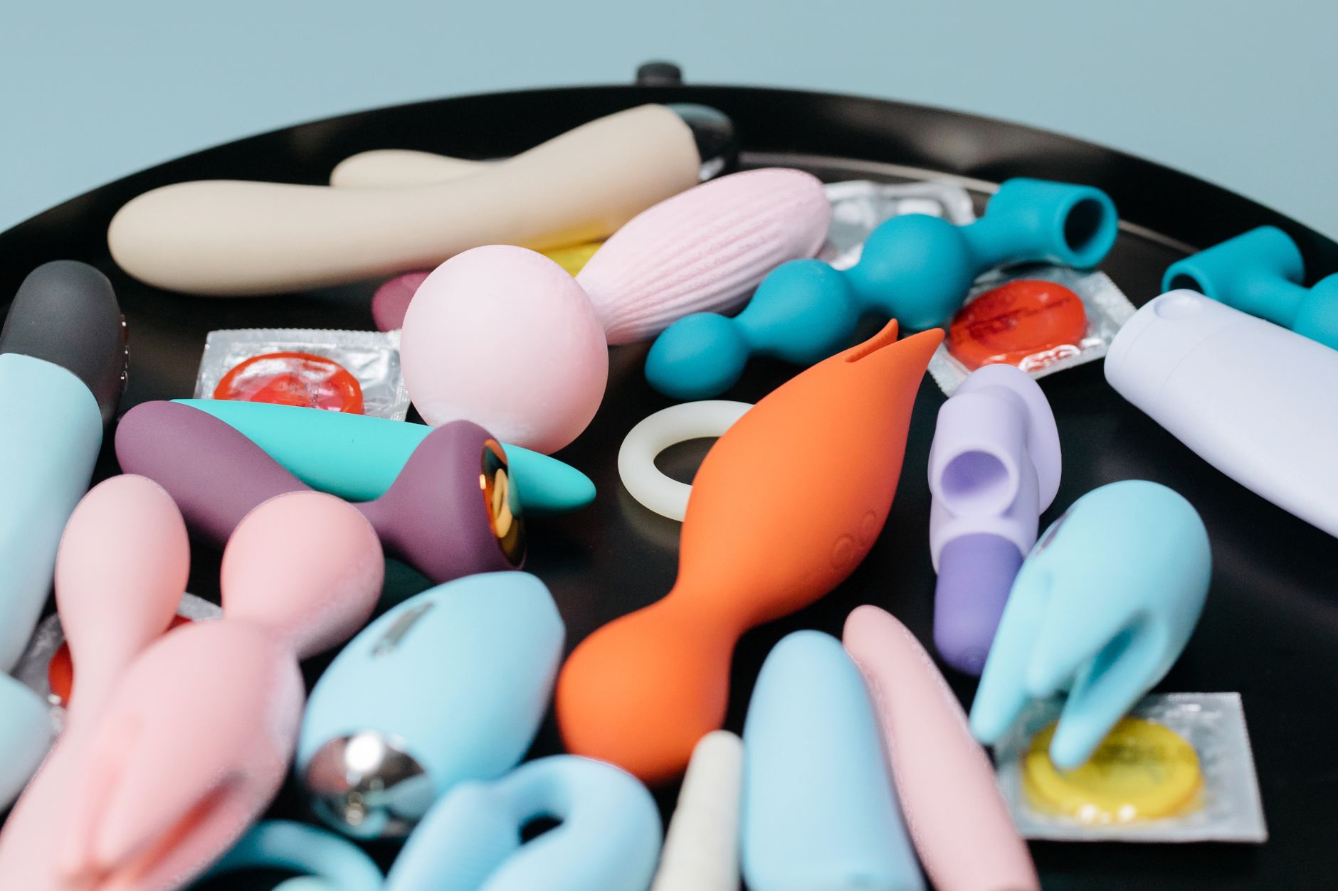 A collection of various colorful vibrators and adult toys on a dark surface