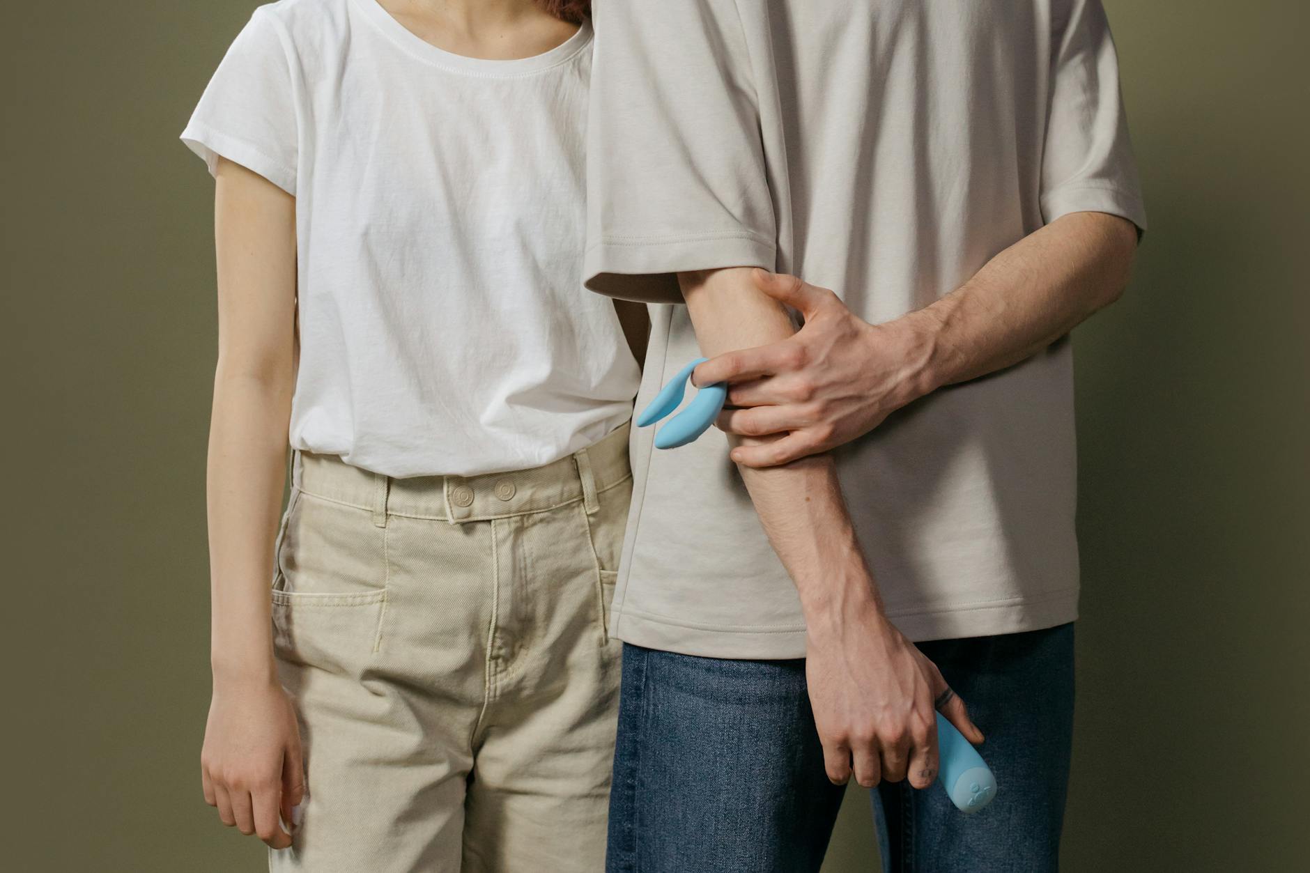 A blue silicone vibrator held in hand against a purple background