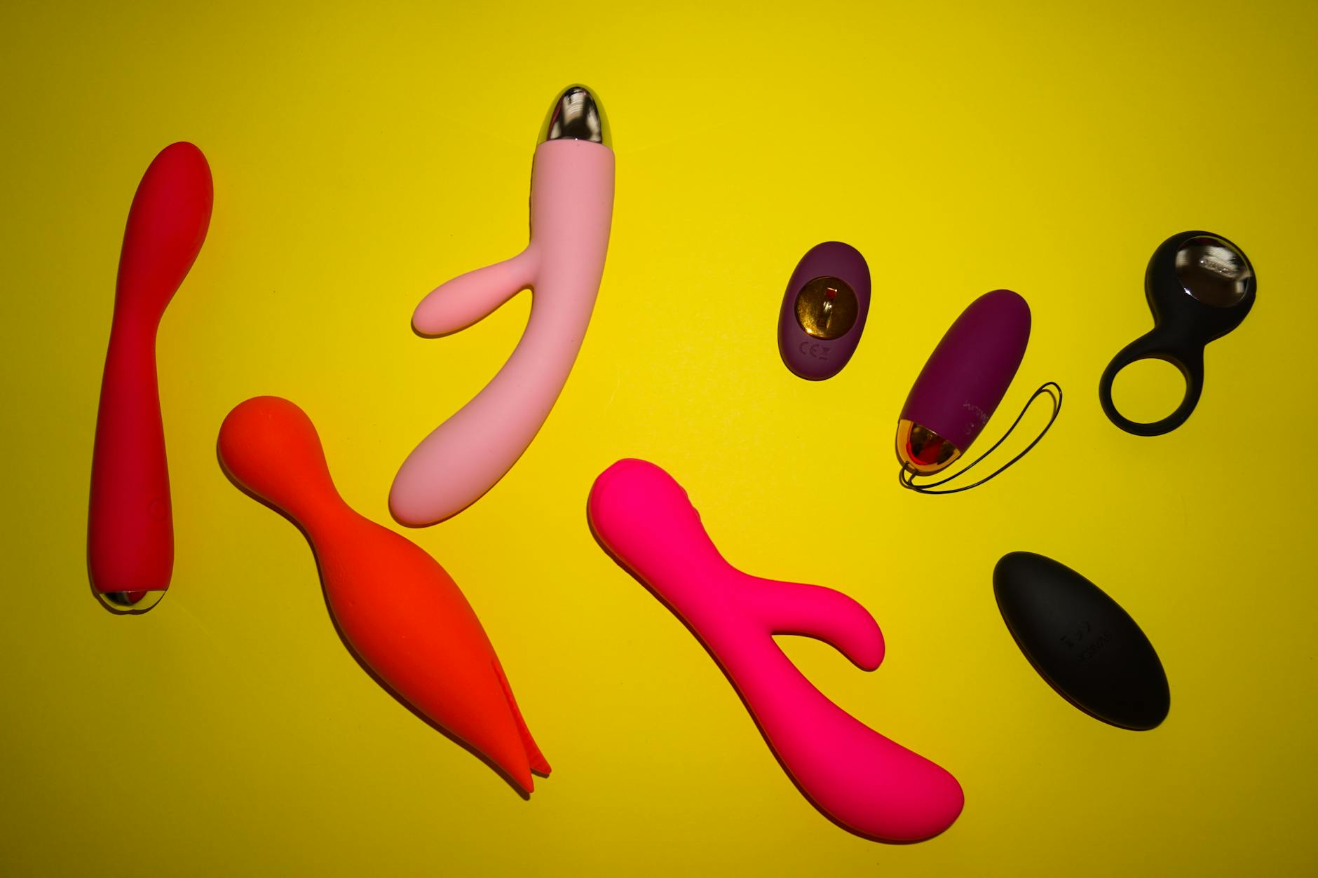 Yellow silicone vibrator surrounded by fresh fruit on a yellow background