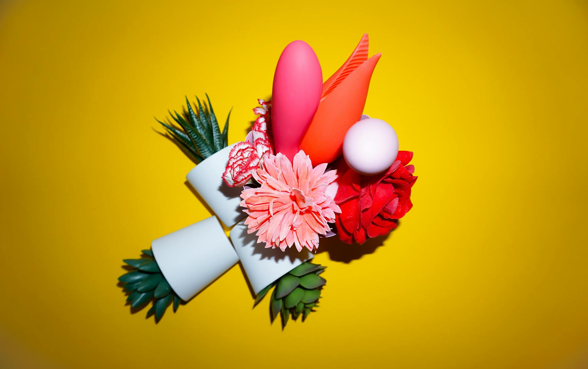 Yellow silicone vibrator surrounded by fresh fruit on bright yellow background
