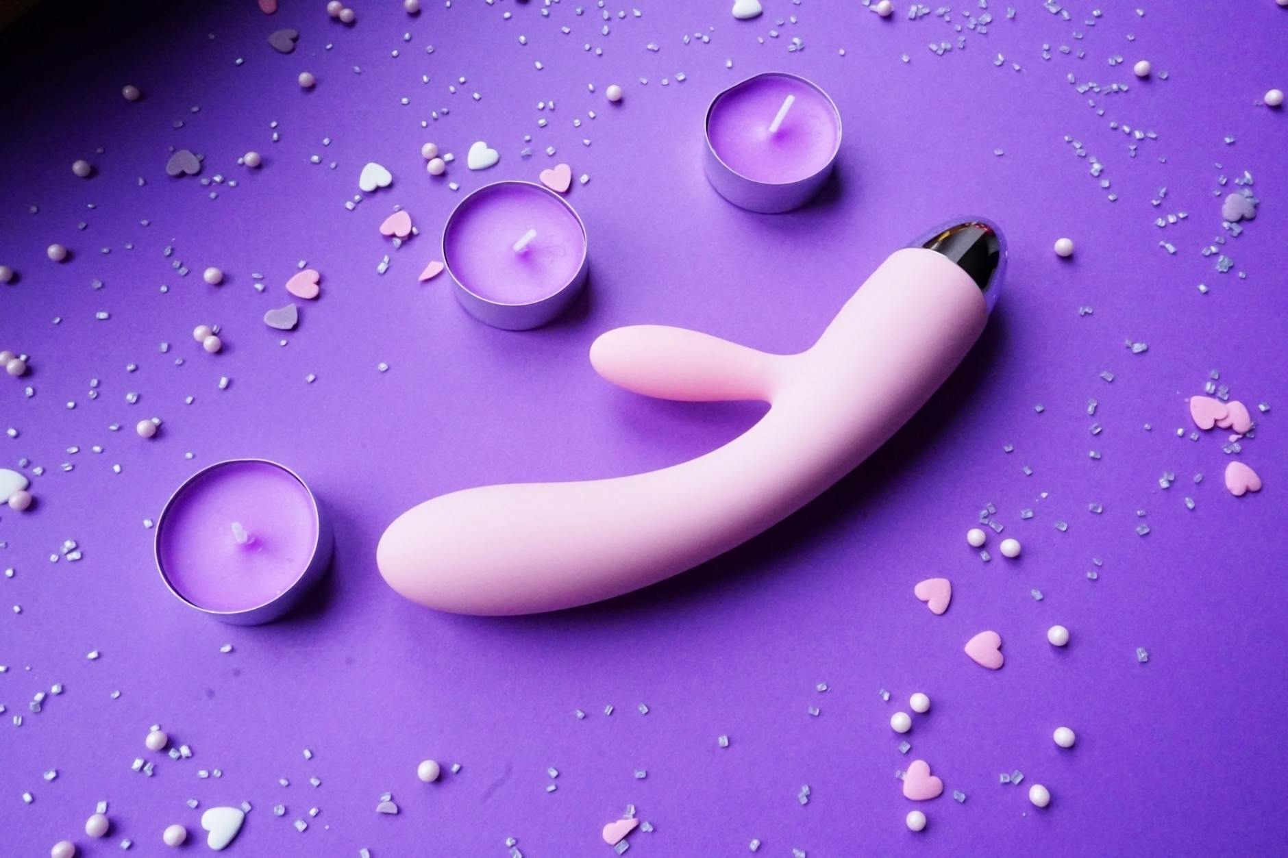 A blue silicone lemon clitoral vibrator held in hand against a purple background
